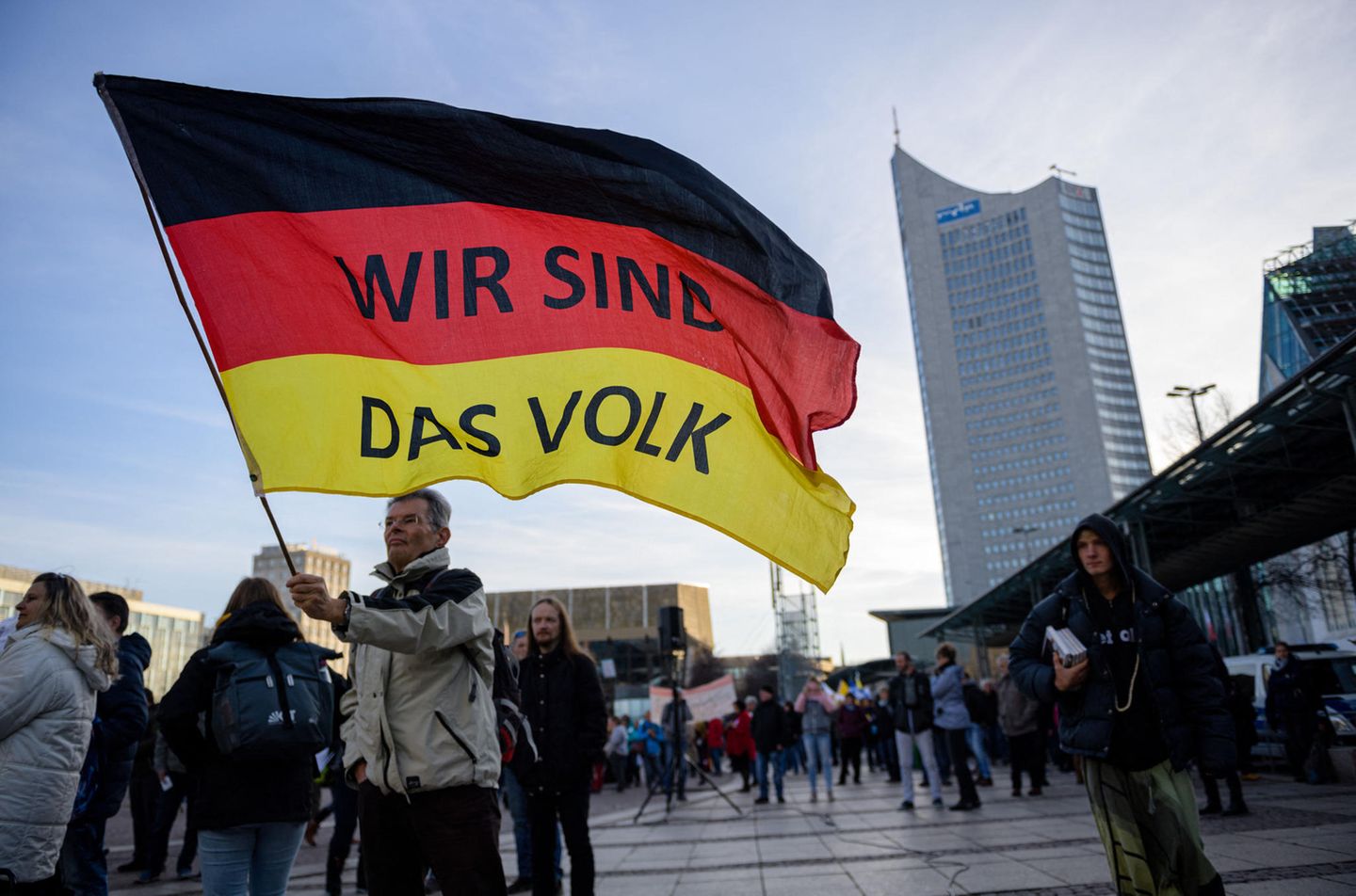 “Wir sind das Volk” steht auf einer riesigen Deutschland Flagge die ein älterer Mann bei einer Querdenkerdemonstration 2021 in Leipzig schwingt. Dieses durch solche Parolen vermittelte Zugehörigkeitsgefühl, kann sehr attraktiv auf einsame Menschen wirken 