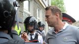 Alexej Nawalny trägt ein Poloshirt, um ihn herum sind Polizisten mit Helmen