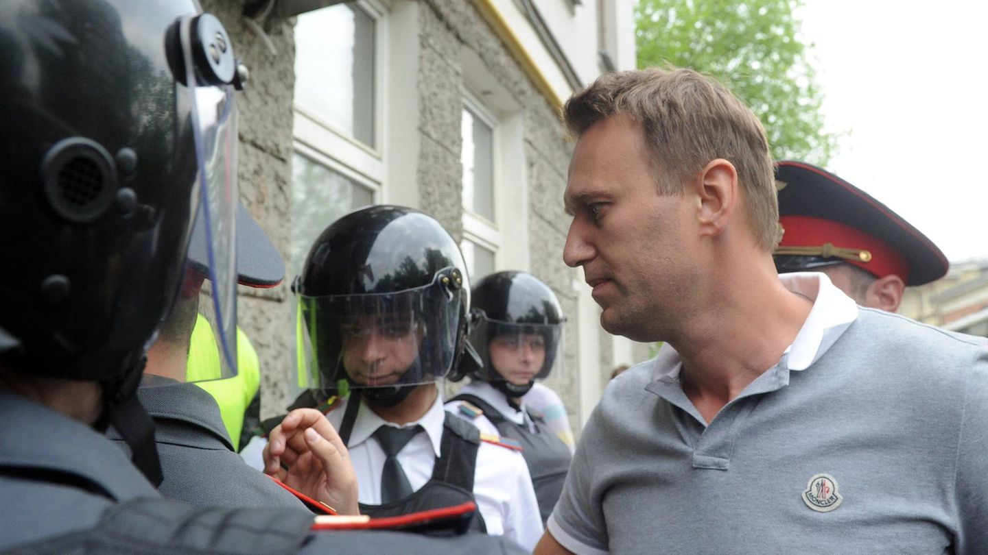 Alexej Nawalny trägt ein Poloshirt, um ihn herum sind Polizisten mit Helmen