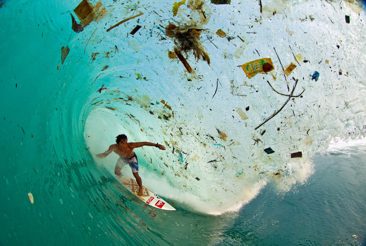 2013 – Indonesien Der Surfer erwischt eine Welle, die sehr viel Müll mit sich trägt.