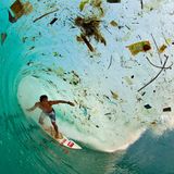 Der Surfer erwischt eine Welle, die sehr viel Müll mit sich trägt.