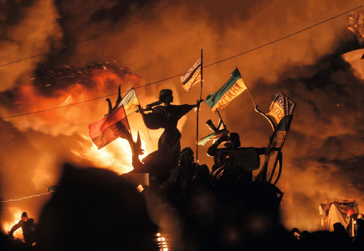 2014 – Ukraine Proteste im dunkeln. Fahnen wehen im Wind während diese vom Feuer von hinten beleuchtet werden.