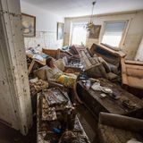 Eine Frau sitzt inmitten ihres von einer Flut zerstörten Wohnzimmers