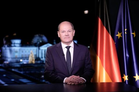 Olaf Scholz sitzt bei der Neujahrsansprache vor einer Deutschland- und Europa-Flagge