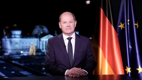 Olaf Scholz sitzt bei der Neujahrsansprache vor einer Deutschland- und Europa-Flagge