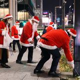 Menschen in Weihnachts-Kostümen sammeln Müll