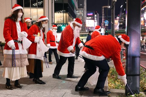 Menschen in Weihnachts-Kostümen sammeln Müll