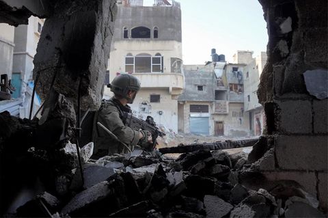 Ein israelischer Soldat läuft mit einem Maschinengewehr durch kaputte Gebäude im Gazastreifen