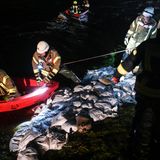 Einsatzkräfte flicken die Löcher im Deich mit gefüllten Sandsäcken