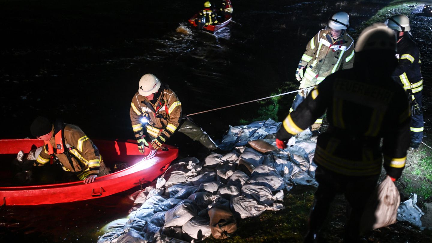 Einsatzkräfte flicken die Löcher im Deich mit gefüllten Sandsäcken