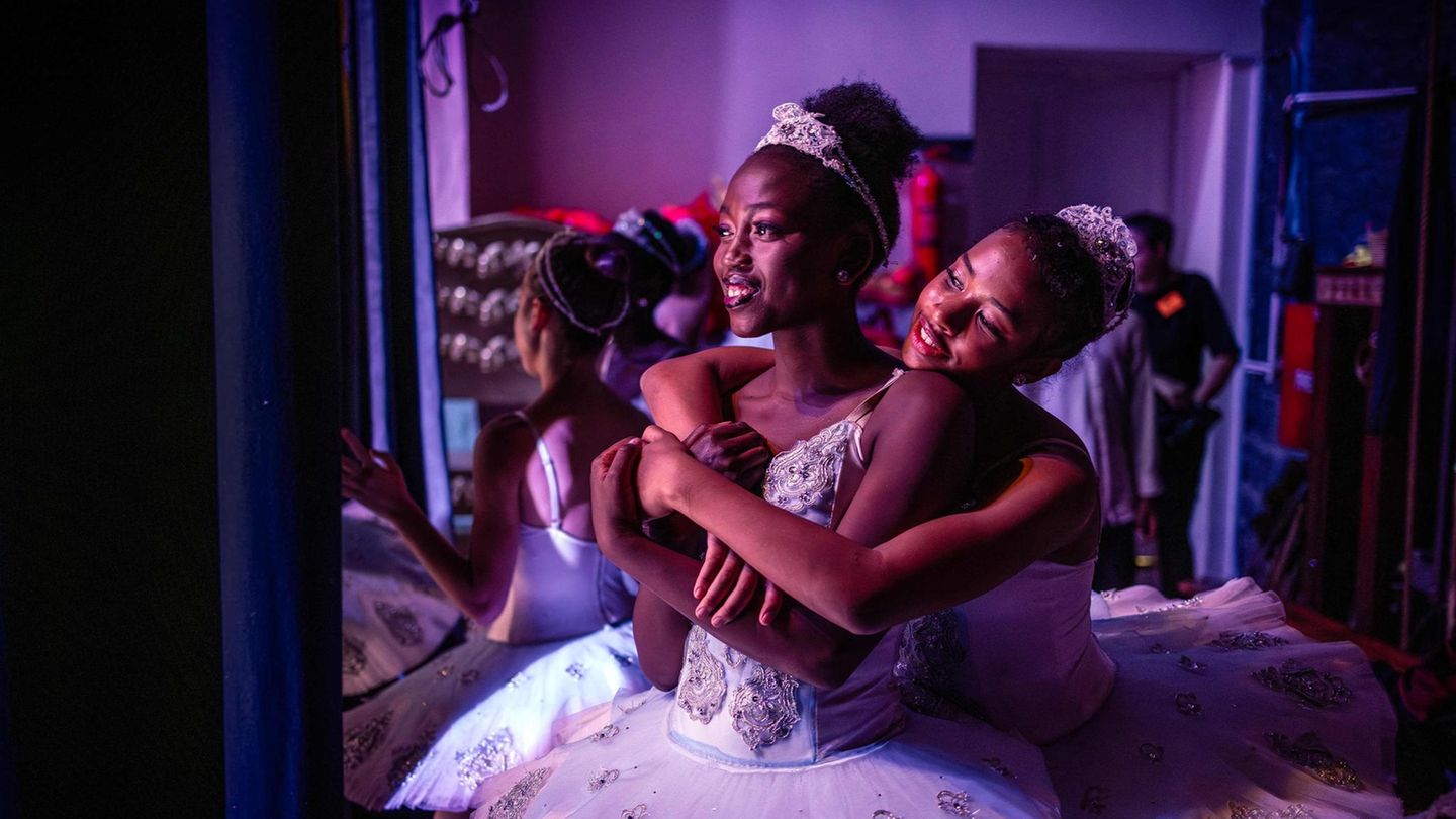 Noch mehr Primaballerinen Die Tänzerinnen Pauline Okumu (M.) und Natalia Como (r.) umarmen sich hinter der Bühne während einer Aufführung von "Der Nussknacker" im Kenya National Theatre in Nairobi. Das Dance Centre Kenya (DCK) hat sich zu Kenias führender und vielseitigster Tanzschule entwickelt, die es sich zur Aufgabe gemacht hat, talentierte Tänzerinnen und Tänzer auszubilden – unabhängig davon, ob sie sich die Ausbildung leisten können oder nicht. Das Patenschaftsprogramm des DCK hat sich bereits auf das Leben vieler aufstrebender Tänzerinnen und Tänzer aus benachteiligten Verhältnissen ausgewirkt, von denen einige an Ausbildungsprogrammen renommierter internationaler Ballettschulen im Ausland teilgenommen haben.