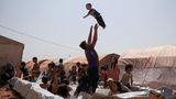 Kinder spielen in einem behelfsmäßigen Pool in einem Lager für Binnenvertriebene