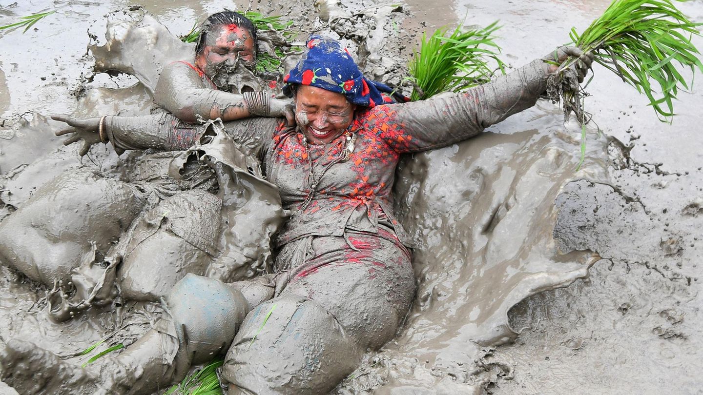 Mit Schlamm bedeckte Bäuerinnen spielen in einem Reisfeld in Nepal