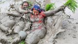 Mit Schlamm bedeckte Bäuerinnen spielen in einem Reisfeld in Nepal