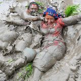 Mit Schlamm bedeckte Bäuerinnen spielen in einem Reisfeld in Nepal