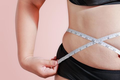 Übergewicht: Eine Frau hält ein Maßband an ihre Taille