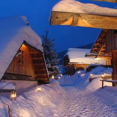 Almdorf Seinerzeit in Kärnten: Hütten im Tiefschnee bei Dämmerung
