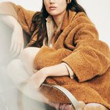 Gloria-Sophie Burkandt Eine Frau mit langen Haaren trägt einen Mantel und schaut in die Kamera