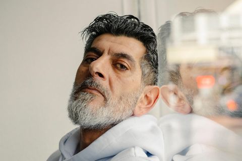 Cetin Gültekin lehnt an ein Fenster und schaut in die Kamera