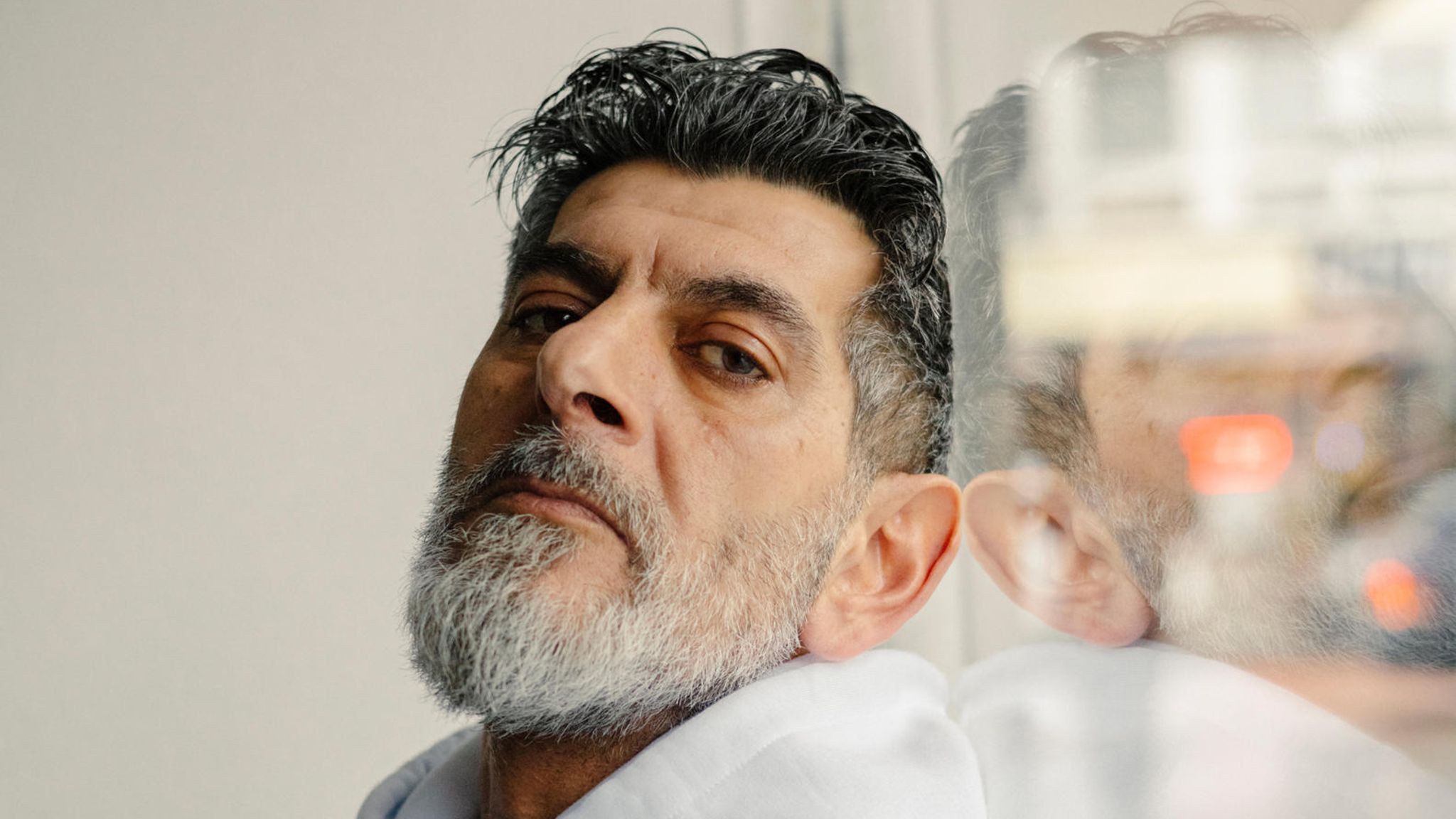 Cetin Gültekin lehnt an ein Fenster und schaut in die Kamera