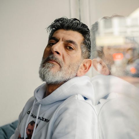 Cetin Gültekin lehnt an ein Fenster und schaut in die Kamera