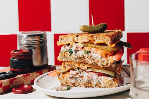 Tuna-Salad-Melt  Dieser Thunfischsalat ist unheimlich vielseitig. Hier spielt er die Hauptrolle in einem Schmelzkäse­-Sandwich, er passt aber auch zu anderen Sandwich­-Kombinationen, in eine Buddha-Bowl und ist auch eine tolle Beilage. Gönn ihm auf jeden Fall eine gute Mayonnaise oder mach sie am besten selbst!     Zutaten:  Vegane Mayo  60 ml Sojamilch  3⁄4 TL Apfel- oder Weißweinessig   1⁄4 TL Dijon-Senf  1⁄4 TL Knoblauchpulver  1⁄4 TL Meersalz  190 ml Rapsöl oder anderes neutrales Pflanzenöl     Thunfischsalat   1 1⁄4 EL Dulse-Flocken (zerkleinerte, essbare Algen)  frisch gepresster Zitronensaft von 1⁄2 Zitrone  1 Prise Natriumglutamat  80 g Soja-Hack   1⁄4 TL Meersalz   1⁄4 TL Chiliflocken  1⁄2 Stange Staudensellerie, fein gehackt  1⁄2 TL Dijon-Senf     2 TL gehackter Dill     2 TL gehackte glatte Petersilie   2 EL gewürfelte rote Zwiebel     Tuna Melt  3 EL vegane Butter oder vegane Mayonnaise  8 Scheiben Brot    8 Scheiben veganer Cheddar  2 Tomaten, in Scheiben geschnitten  4 Dillgurken, in Scheiben geschnitten     Zubereitung:  Für die Mayonnaise alle Zutaten bis auf das Öl in einem hohen Messbecher mit dem Pürierstab etwa 20 Sekunden schaumig aufschlagen. Das Öl bei laufendem Pürierstab über 1–2 Minuten langsam, aber stetig einträufeln, bis sich alles zu einer dicken Mayonnaise verbindet. Abschmecken und falls nötig nachwürzen. Die Mayonnaise hält sich in einem luftdicht schließenden Behälter im Kühlschrank bis zu 1 Monat.  Für den Thunfischsalat Dulse-Flocken, Zitronensaft und Natriumglutamat in einer Schüssel mit 125 ml kochend heißem Wasser verquirlen. Das Soja-Hack 15 Minuten darin quellen lassen. 60 g der Mayo dazugeben und mit den restlichen Zutaten für den Salat vermengen. Mindestens 1 Stunde im Kühlschrank ziehen lassen. Kalt servieren oder als Belag für das Tuna-Melt-Sandwich verwenden.  Die Brotscheiben jeweils auf einer Seite mit Butter oder Mayonnaise bestreichen. Für das Sandwich eine Scheibe mit der Butterseite nach unten hinlegen, mit vier Scheiben Käse belegen, je ein Viertel des Salats, der Tomatenscheiben und der Dillgurken und weiteren Käse darauf schichten und die letzte Brotscheibe mit der Butter nach oben darauf legen.  Den Backofengrill vorheizen und das Sandwich auf oberster Schiene von beiden Seiten etwa 6 Minuten grillen, bis der Käse verlaufen und das Brot golden ist. Das Sandwich gut im Auge behalten, damit es nicht verbrennt.