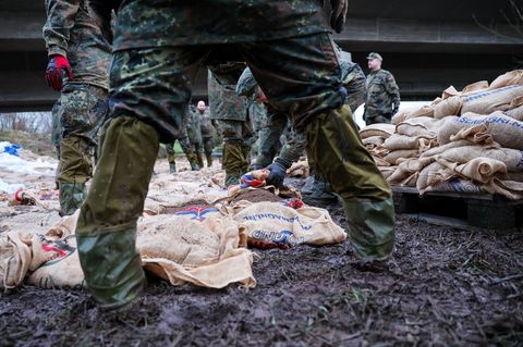 Soldatinnen und Soldaten der Bundeswehr sichern einen Deich im Hochwassergebiet mit Sandsäcken