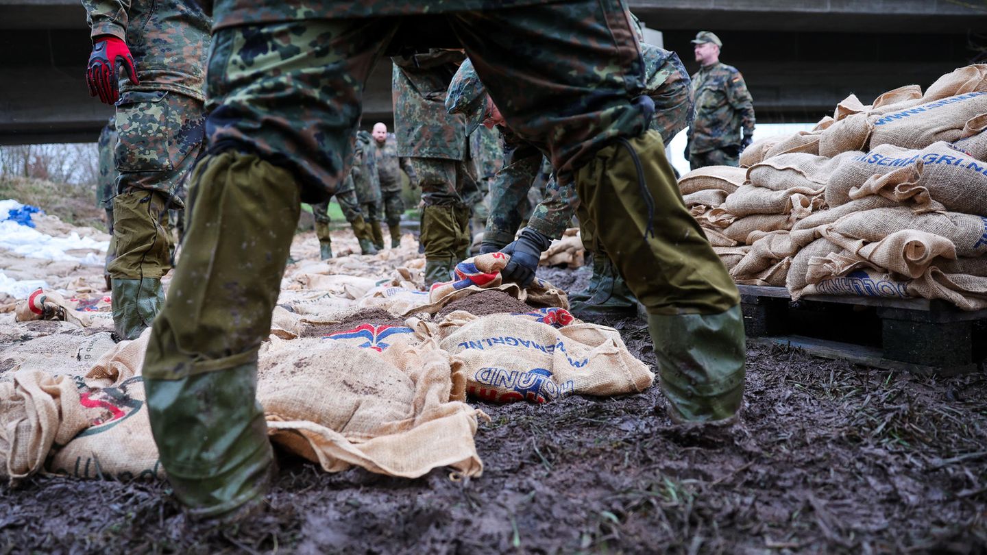 Soldatinnen und Soldaten der Bundeswehr sichern einen Deich im Hochwassergebiet mit Sandsäcken