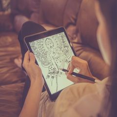 Eine Frau zeichnet eine Figur auf ihrem Paper-Tablet