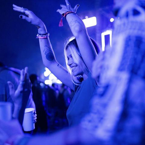 Ein londes Mädchen tanzt im Club in einer Menschenmenge