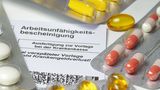 Medikamentenblister liegen auf einer Arbeitsunfähigkeitsbescheinigung