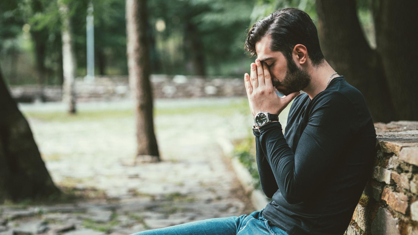 Ein Mann sitzt allein auf einer Bank im Wald