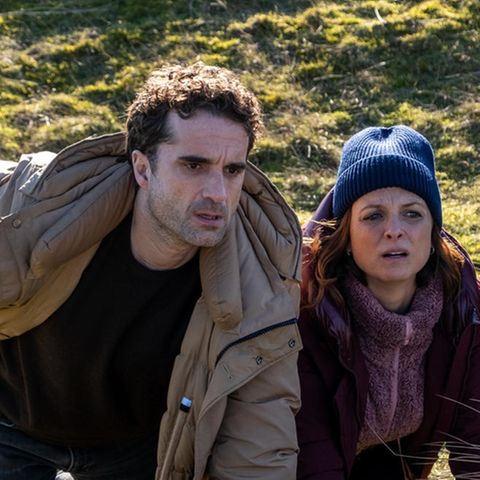 Carl Sievers (Peter Heinrich Brix, r.), Hinnerk Feldmann (Oliver Wnuk) und Ina Behrendsen (Julia Brendler) suchen Schutz hinter einem Hügel in einer Szene des Films "Nord Nord Mord - Sievers und die fünf Fragezeichen"
