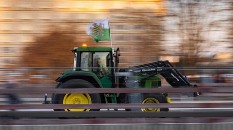 Ein Landwirt fährt mit seinem Traktor und einer Fahne des einstigen Königreiches Sachsen zu sehen. Die Fahnen werden häufig von Anhängern der rechtsextremen Kleinstpartei Freie Sachsen mitgeführt     