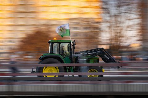 Ein Landwirt fährt mit seinem Traktor und einer Fahne des einstigen Königreiches Sachsen zu sehen. Die Fahnen werden häufig von Anhängern der rechtsextremen Kleinstpartei Freie Sachsen mitgeführt     