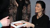 Sahra Wagenknecht reicht lächelnd ein von ihr signiertes Buch an einen Fan