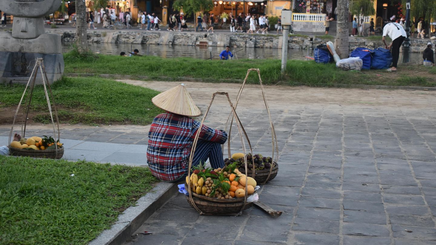 Einheimischer sitzt auf dem Boden mit Obstkörben
