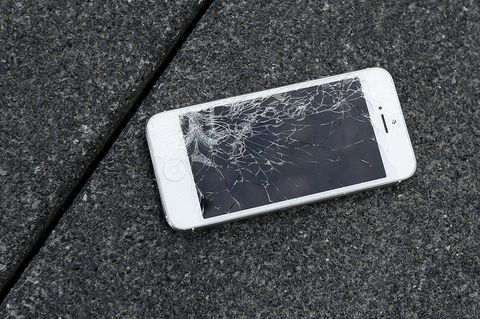 Ein iPhone liegt mit kaputtem Display auf einem Steinboden