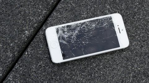 Ein iPhone liegt mit kaputtem Display auf einem Steinboden