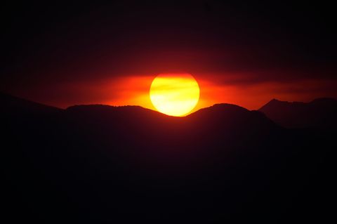 Die Sonne leuchtet als roter Feuerball über den Rocky Mountains