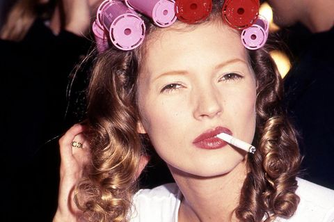 Kate Moss backstage bei einer Modenschau mit Lockenwicklern in den Haaren