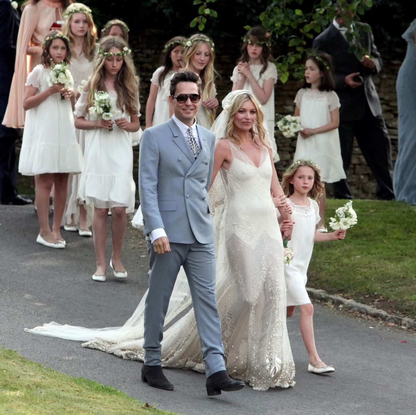 Hochzeit von Kate Moss und Jamie Hince, sie im weißen Kleid mit Glitzer und Schleier, er im hellen Anzug mit Sonnenbrille