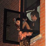 Pete Doherty, Kate Moss und Mick Whitnall in einem Fenster. Doherty hält eine Gitarre in der Hand