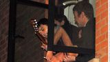 Pete Doherty, Kate Moss und Mick Whitnall in einem Fenster. Doherty hält eine Gitarre in der Hand