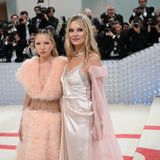 Kate und Lila Moss, Mutter und Tochter, stehen in edlen Kleidern nebeneinander vor einer Treppe. Im Hintergrund Fotografen.