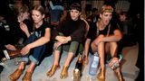 Kate Moss, Christy Turlington und Linda Evangelista sitzen nebeneinander auf dem Boden. Ihre Füße sind Gold eingesprüht.