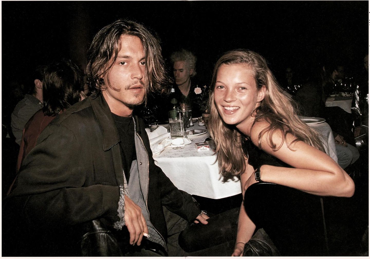 Kate Moss und Johnny Depp sitzen an einem Tisch und schauen in die Kamera