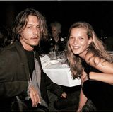 Kate Moss und Johnny Depp sitzen an einem Tisch und schauen in die Kamera