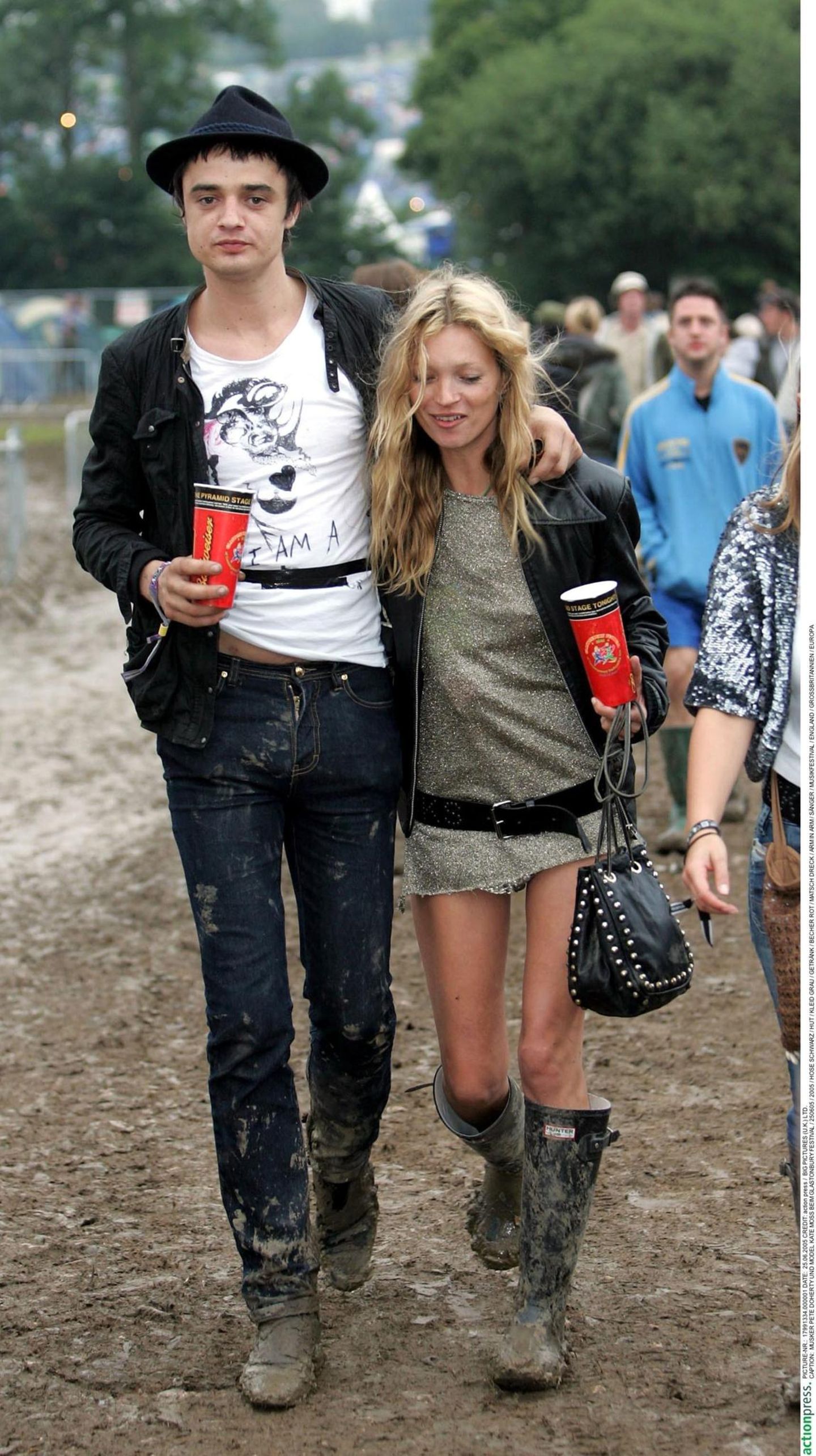Kate Moss und Pete Doherty gehen eng beisammen über ein Schlammfeld bei einem Festival