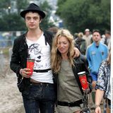 Kate Moss und Pete Doherty gehen eng beisammen über ein Schlammfeld bei einem Festival